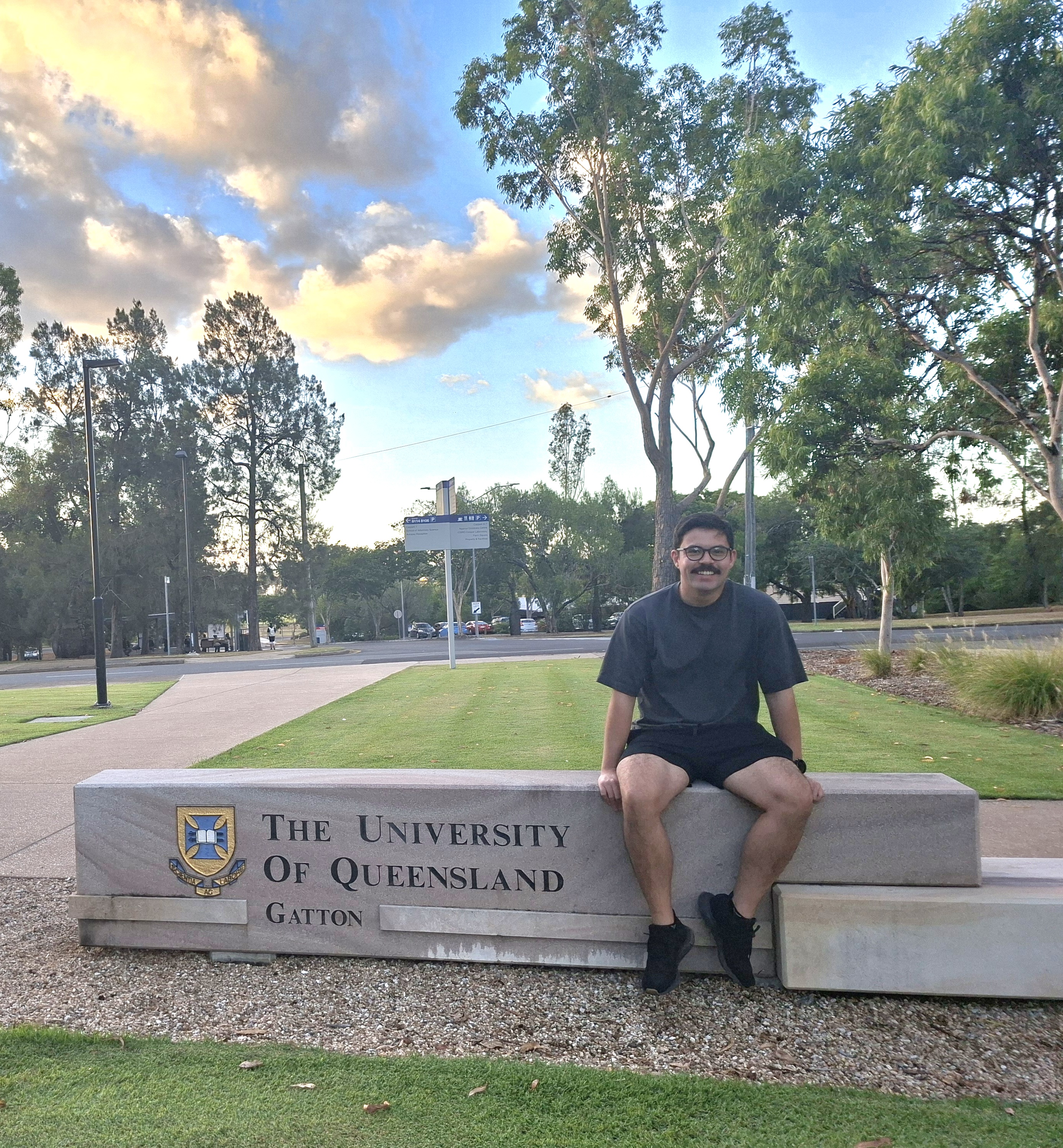 Robert Spencer seated on the University of Queensland Gatton campus entrance sign